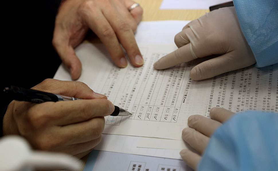 Shanghai, april 2021. Een patiënt wordt geholpen bij het invullen van een informed consent formulier.