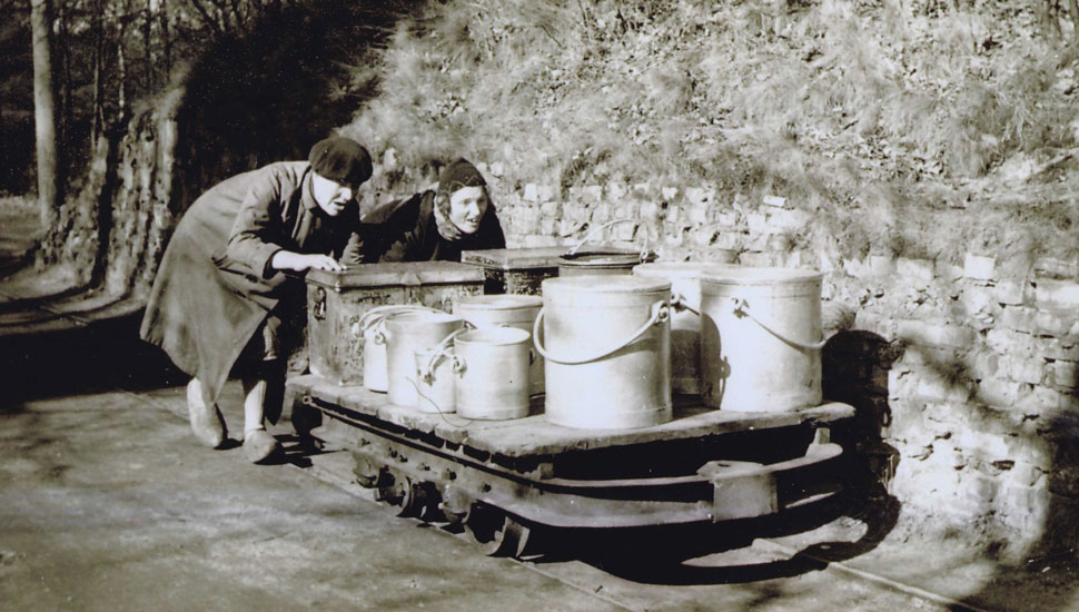 Patiënten van de Willem Arntsz Hoeve duwen een lorrie met voeding naar patiënten­paviljoens, medio 1930.