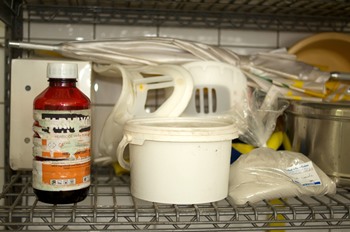 Een fles herbicide en een zak Fullerse aarde in het spoelhok van het ziekenhuis in Nickerie.