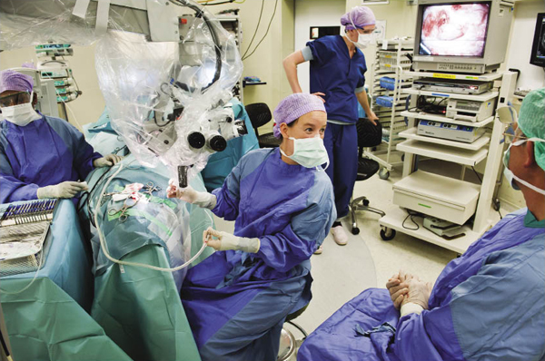 Een meisje ondergaat een ooroperatie in het AMC. De ingreep wordt grotendeels uitgevoerd door een chirurg in opleiding, met behulp van een operatiemicroscoop. De verantwoordelijk chirurg volgt de operatie via het televisiescherm. Beeld: Sake Rijpkema, HH