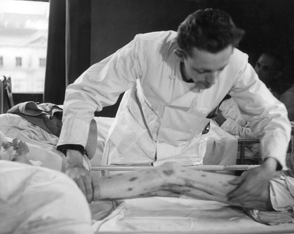 Een arts bekijkt na de bevrijding in 1945 een been van een uitgehongerd mens, als gevolg van de beruchte hongerwinter van 1944-1945. Amsterdam, juni 1945. Beeld: Hollandse Hoogte